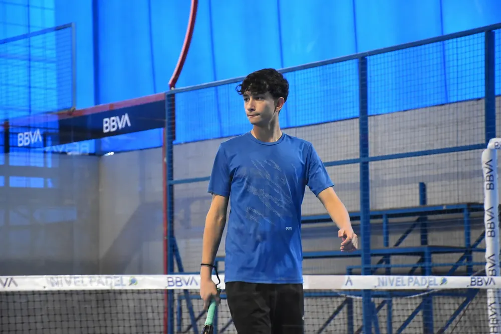 Joven jugador en pista de pádel azul